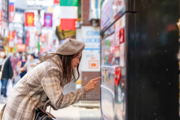 Mulher asiática comprando bebidas em máquina de venda automática no distrito de Shibuya, Tóquio, Japão.