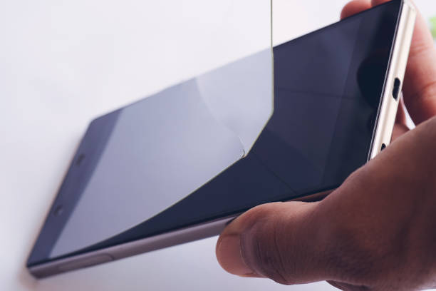 يد تزيل فيلم حماية شاشة الهاتف المتضرر والملطخ