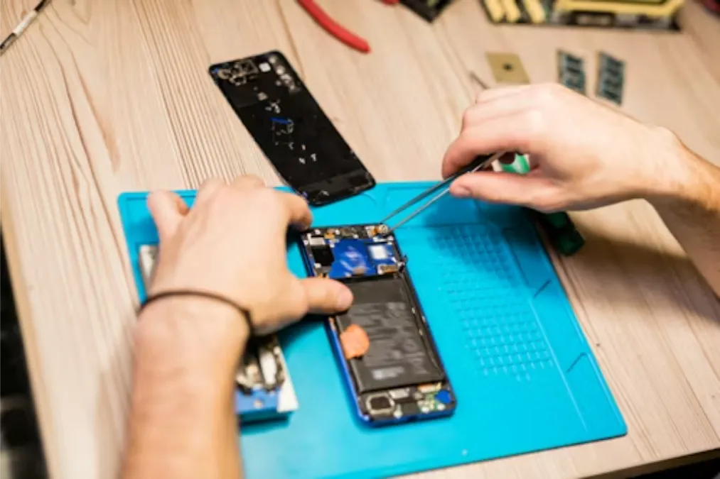 Hands-of-repairman-over-broken-gadget-using-tweezers-to-fix-tiny-parts-or-bolts-of-demounted-smartphone_1779078294