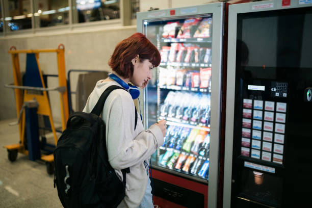 Side view of a young happy Caucasian woman looking at a vending machine